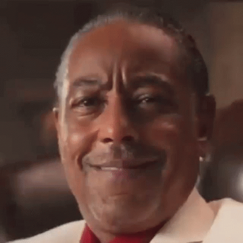 A Man Wearing A White Jacket And A Red Tie Smiles For The Camera GIF