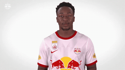 A Man Wearing A White Jersey With Red Bulls On The Front GIF