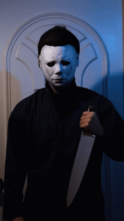 A Man Wearing A White Mask Holds A Gun GIF