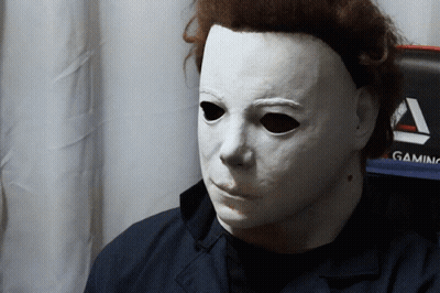 A Man Wearing A White Mask Is Sitting In Front Of A Gaming Monitor GIF