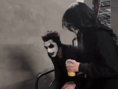 A Man Wearing A White Mask Is Sitting Next To A Woman GIF