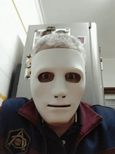 A Man Wearing A White Mask Is Standing In Front Of A Fridge That Has A Picture Of A Cat On It GIF