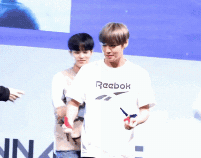 A Man Wearing A White Reebok T-Shirt Stands Next To Another Person GIF