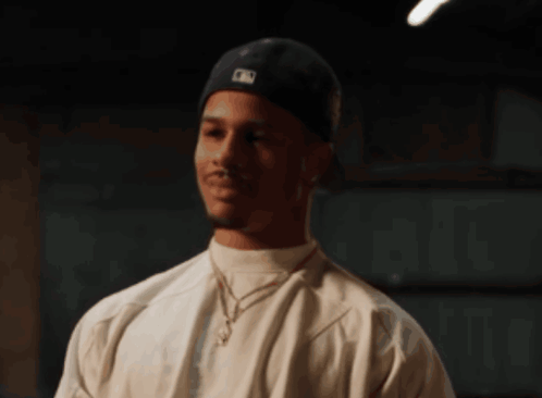 A Man Wearing A White Shirt And A Black Hat Has A Mlb Logo On His Hat GIF