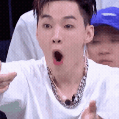 A Man Wearing A White Shirt And A Chain Necklace Is Making A Funny Face . GIF