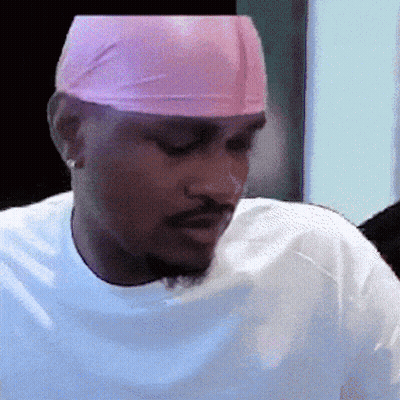 A Man Wearing A White Shirt And A Pink Headband Looks Down GIF