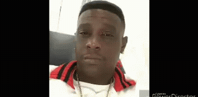A Man Wearing A White Shirt And A Red Jacket Is Looking At The Camera . GIF