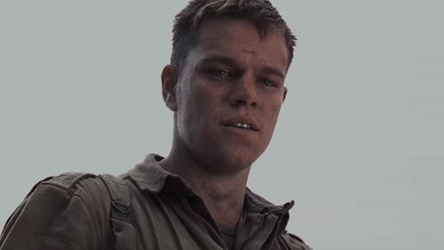 A Man Wearing A White Shirt And A Silver Jacket Looks At The Camera GIF
