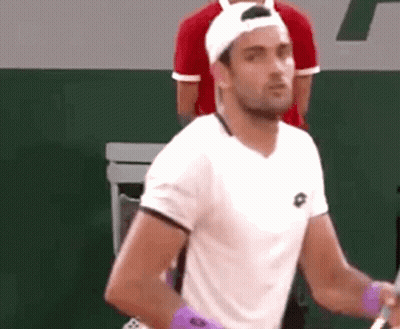 A Man Wearing A White Shirt And A White Hat Is Holding A Tennis Racket . GIF