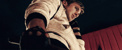 A Man Wearing A White Shirt And Black Gloves Looks Down GIF