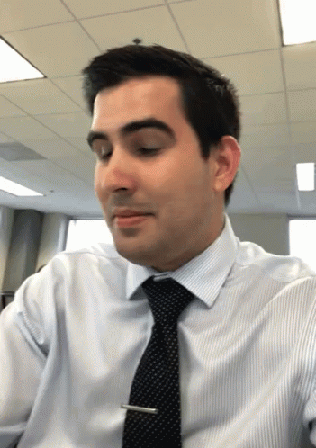 A Man Wearing A White Shirt And Black Tie Looks Down GIF