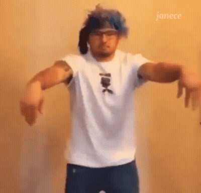 A Man Wearing A White Shirt And Blue Hair Is Dancing . GIF