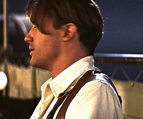 A Man Wearing A White Shirt And Brown Suspenders Looks Down GIF
