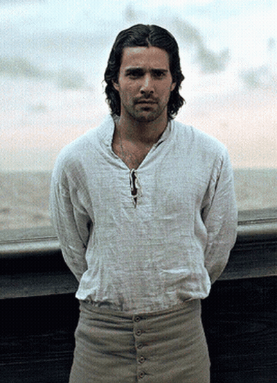 A Man Wearing A White Shirt And Khaki Pants Stands In Front Of A Window GIF