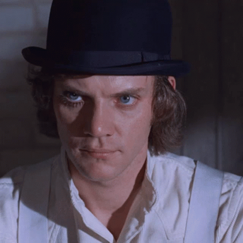 A Man Wearing A White Shirt And Suspenders Is Wearing A Black Top Hat GIF