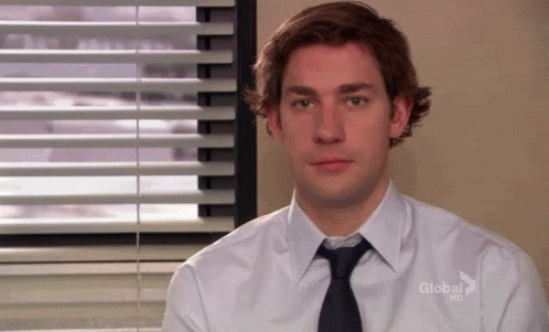 A Man Wearing A White Shirt And Tie Is Sitting In Front Of A Window With Blinds . GIF