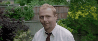 A Man Wearing A White Shirt And Tie Is Standing In A Garden . GIF
