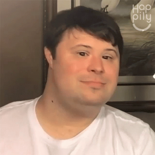 A Man Wearing A White Shirt Is Smiling In Front Of A Picture That Says Hap Pillu On It GIF