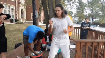 A Man Wearing A White Shirt That Says ' Almost ' On It Stands On A Deck GIF