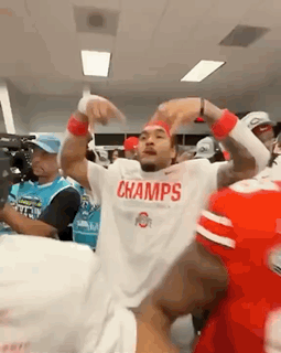 A Man Wearing A White Shirt That Says Champs Is Dancing In A Locker Room GIF