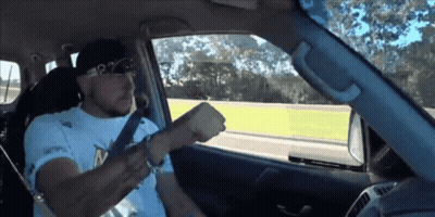 A Man Wearing A White Shirt That Says P2 On It Is Driving A Car GIF