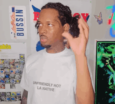 A Man Wearing A White Shirt That Says `` Unfriendly Hot La Native '' GIF