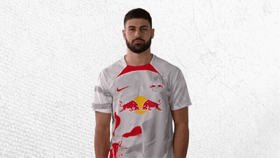 A Man Wearing A White Shirt With A Red Bull On The Front GIF