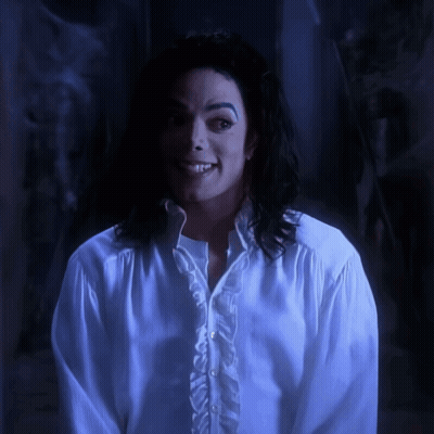 A Man Wearing A White Shirt With Ruffles On The Sleeves Smiles GIF