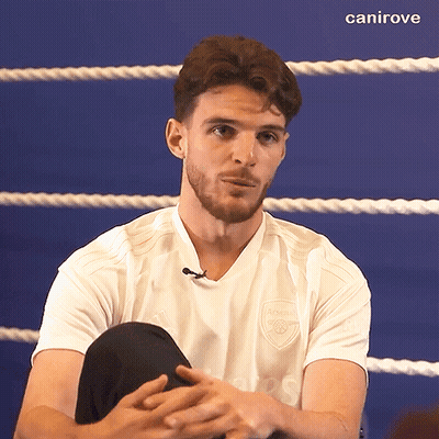 A Man Wearing A White Shirt With The Word Arsenal On It Sits In A Boxing Ring GIF