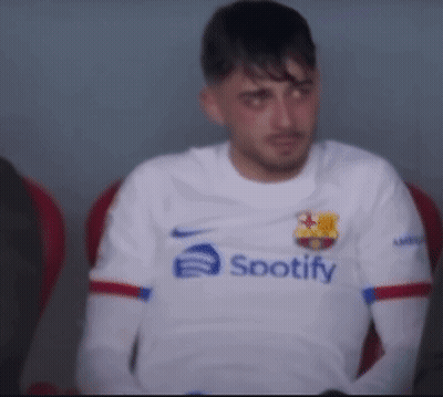 A Man Wearing A White Spotify Shirt Sits In A Chair GIF