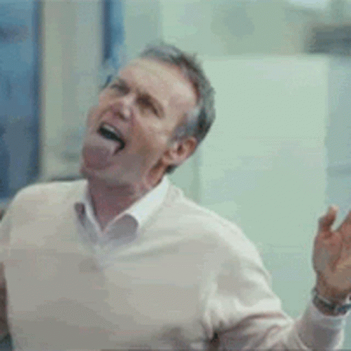 A Man Wearing A White Sweater Is Making A Funny Face GIF