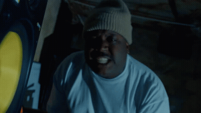 A Man Wearing A White T-Shirt And A Beanie Has A Sticker On His Hat That Says Supreme GIF