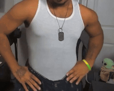 A Man Wearing A White Tank Top And A Dog Tag On His Neck Is Standing With His Hands On His Hips . GIF