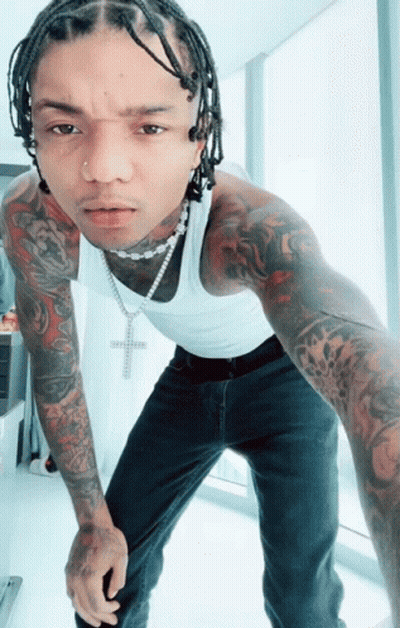 A Man Wearing A White Tank Top And A Necklace With A Cross On It GIF