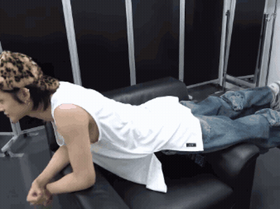A Man Wearing A White Tank Top And Leopard Print Hat Is Laying On A Couch GIF