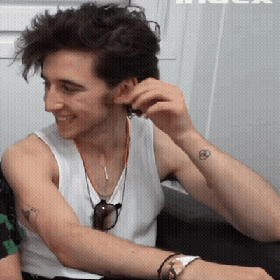 A Man Wearing A White Tank Top Has A Small Tattoo On His Arm GIF