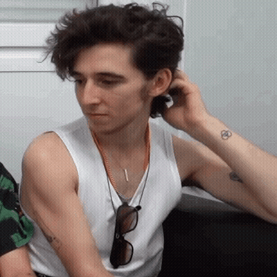 A Man Wearing A White Tank Top Has A Tattoo On His Arm GIF