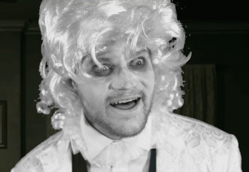 A Man Wearing A White Wig And A White Shirt Is Making A Face GIF