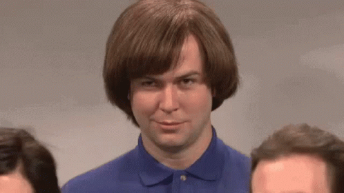 A Man Wearing A Wig And A Blue Shirt Is Standing Next To Two Other Men GIF