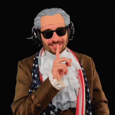 A Man Wearing A Wig And Sunglasses Has His Finger To His Mouth GIF