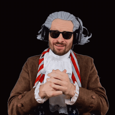 A Man Wearing A Wig And Sunglasses Has His Hands Folded In Front Of Him GIF