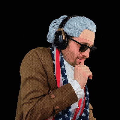 A Man Wearing A Wig And Sunglasses Holds An American Flag Around His Neck GIF