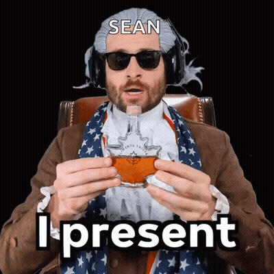 A Man Wearing A Wig And Sunglasses Is Holding A Glass Of Whiskey With The Words Sean I Present Below Him GIF