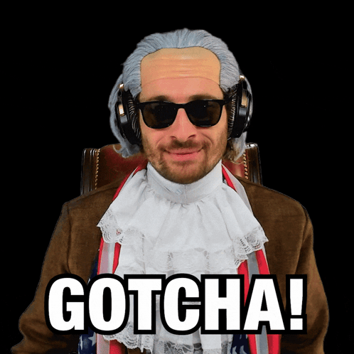 A Man Wearing A Wig And Sunglasses Is Sitting In A Chair And Says Gotcha GIF