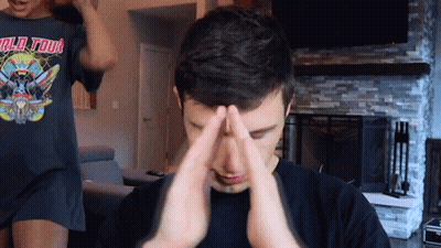 A Man Wearing A World Tour T-Shirt Is Covering His Face With His Hands GIF