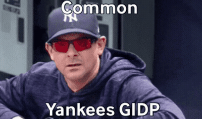 A Man Wearing A Yankees Hat And Red Sunglasses Is Sitting Down . GIF