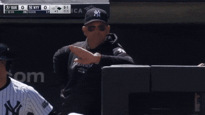 A Man Wearing A Yankees Sweatshirt Is Standing In Front Of A Scoreboard GIF