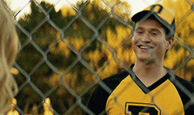 A Man Wearing A Yellow And Black Jersey With The Letter P On It Is Smiling Behind A Chain Link Fence . GIF