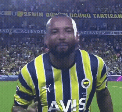 A Man Wearing A Yellow And Blue Striped Shirt With Avis On The Front GIF