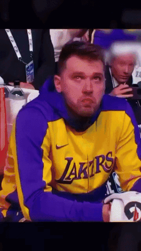 A Man Wearing A Yellow And Purple Lakers Jacket GIF